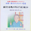 白髪の男性。青いチェックのシャツを着ている。右手に指し棒をもっている。