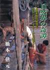 川に上半身裸の男性が浸かっている。男性は小屋に大きな魚をあげている。